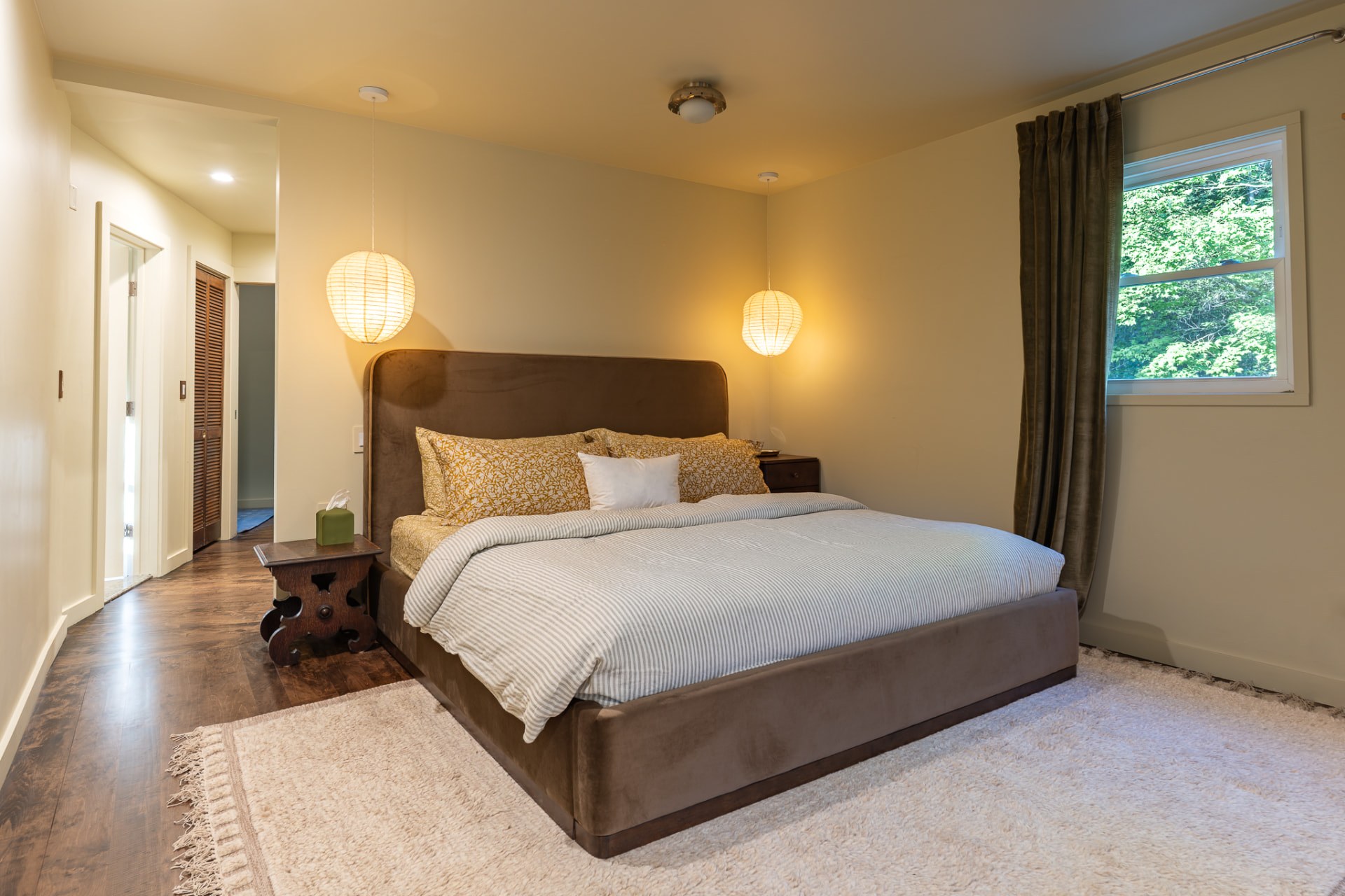 Bedroom with pendant lights and a window overlooking the trees